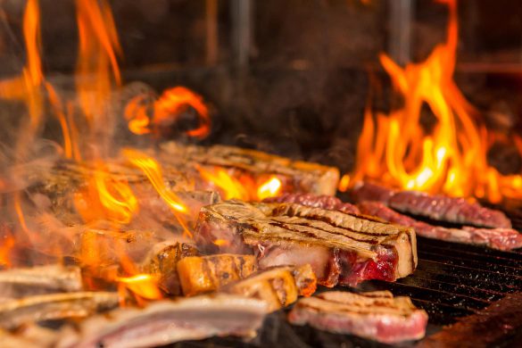 Steak das auf einem Oberhitzegrill brutzelt.