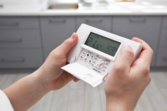 Junge Frau mit einem Raumklimasensor in der Hand.