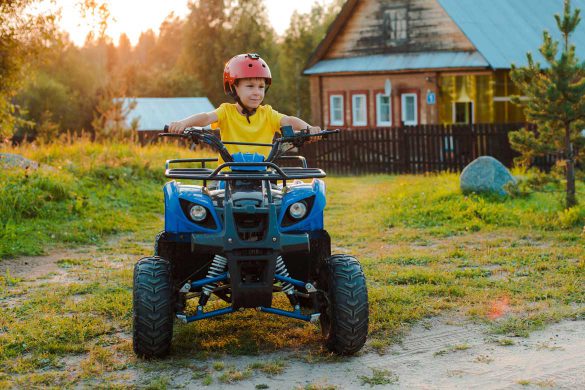 Kleiner Junge fährt auf einem Pocketbike Quad durch den Garten.